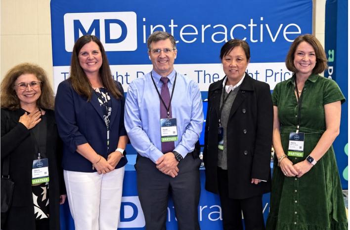 MDinteractive team at the NAACOS Fall Conference standing in front of the MDinteractive booth banner